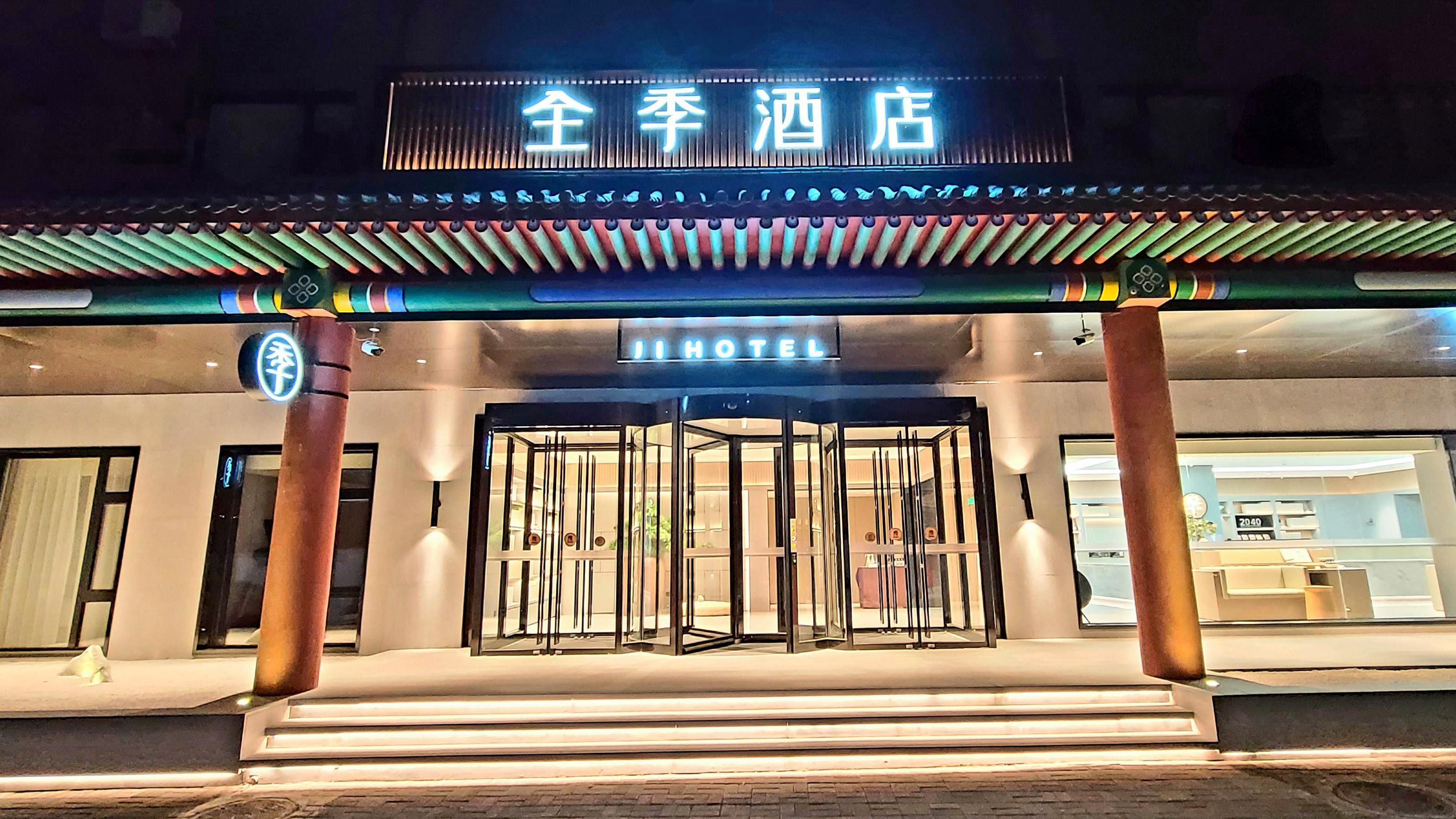 A hotel entrance with a traditional Asian architectural style, a sign indicating it's a hotel, and a revolving door.
