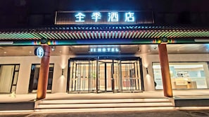 A hotel entrance with a traditional Asian architectural style, a sign indicating it's a hotel, and a revolving door. - Ji Hotel (Beijing)