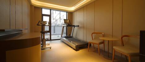 Un gimnasio moderno con una cinta de correr, sillas y un escritorio.