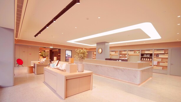 A modern hotel lobby with a reception desk, seating area, and a large digital clock. - Ji Hotel (Beijing)