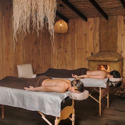 Relax in a serene space with two massage tables, a fireplace, and warm ambiance.