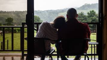 A couple sitting on a bench with a view of a green landscape and hills.