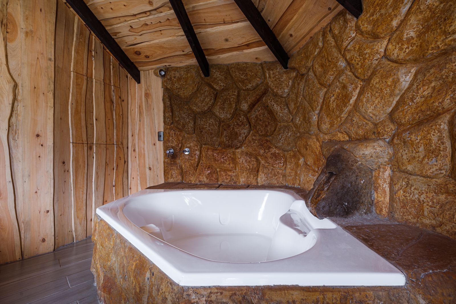 A stone-walled bathroom with a white bathtub.