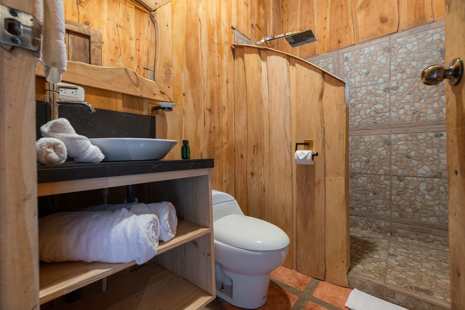 Ein Badezimmer aus Holz mit Waschbecken, Toilette und Dusche.