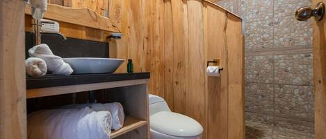 A wooden bathroom with a sink, toilet, and shower.