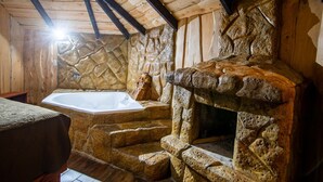 A rustic stone bathroom with a bathtub, wooden beams, and a stone wall. - Hotel & Spa El Escondite de la Montaña (Sabana Redonda)