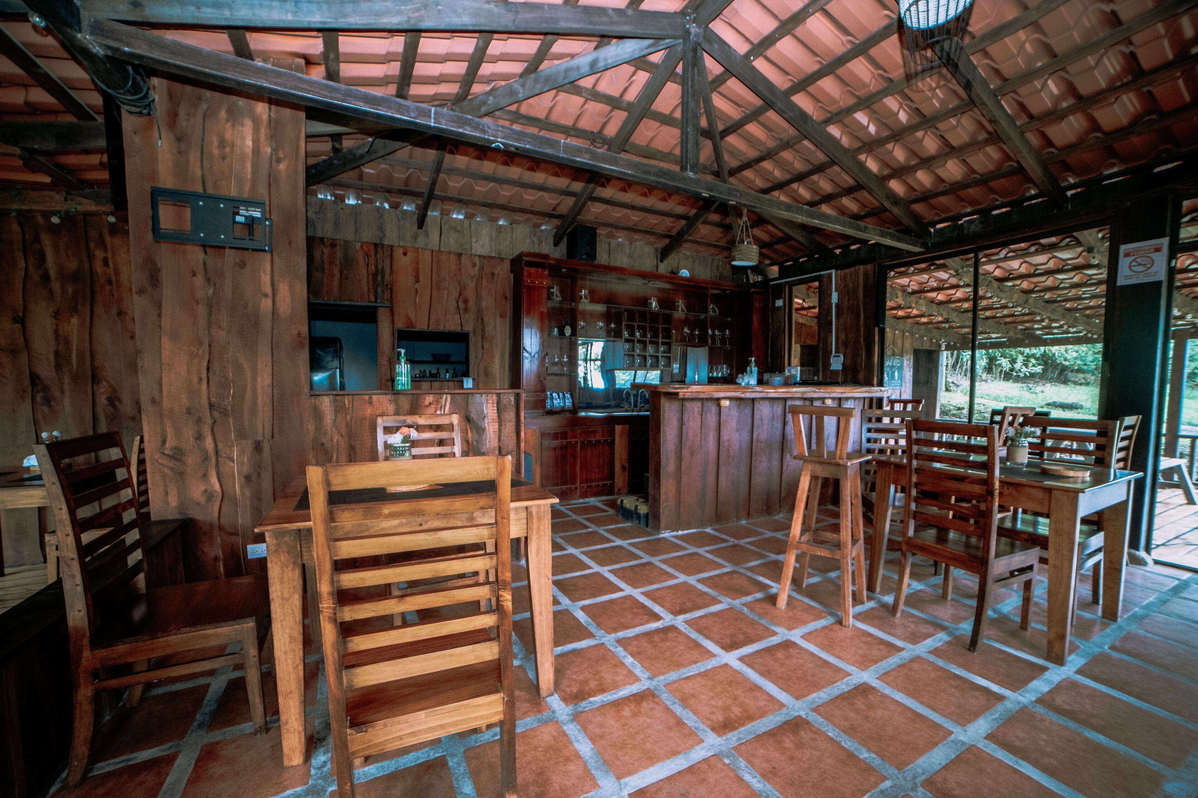 Un interior rústico de madera con suelo de baldosas, muebles de madera y una zona de bar.