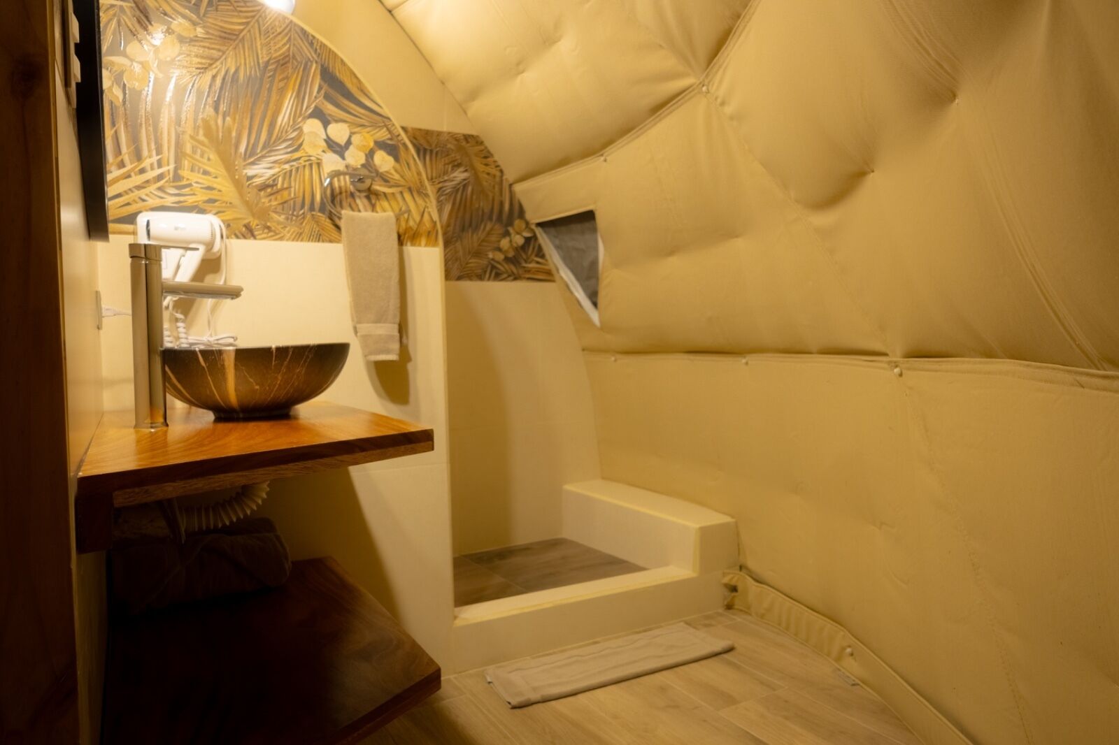 A cozy, compact room with a wooden vanity, a bowl sink, a towel, and a window.