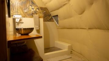A cozy, compact room with a wooden vanity, a bowl sink, a towel, and a window.