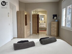 Ein Schlafzimmer mit Bett, Kleiderschrank, Spiegel und Fenster.