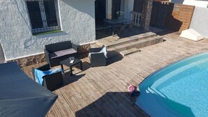 Ett takförsett utomhusområde med en pool, ett trädäck och utomhusmöbler.