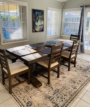 A dining area with a wooden table set for four, surrounded by chairs with cushioned seats.