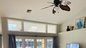 Un salon spacieux avec un canapé en cuir, une table basse en bois et un téléviseur posé sur un meuble en bois.