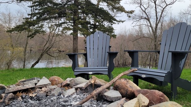 Dues cadires Adirondack al costat d'una foguera en un entorn natural.