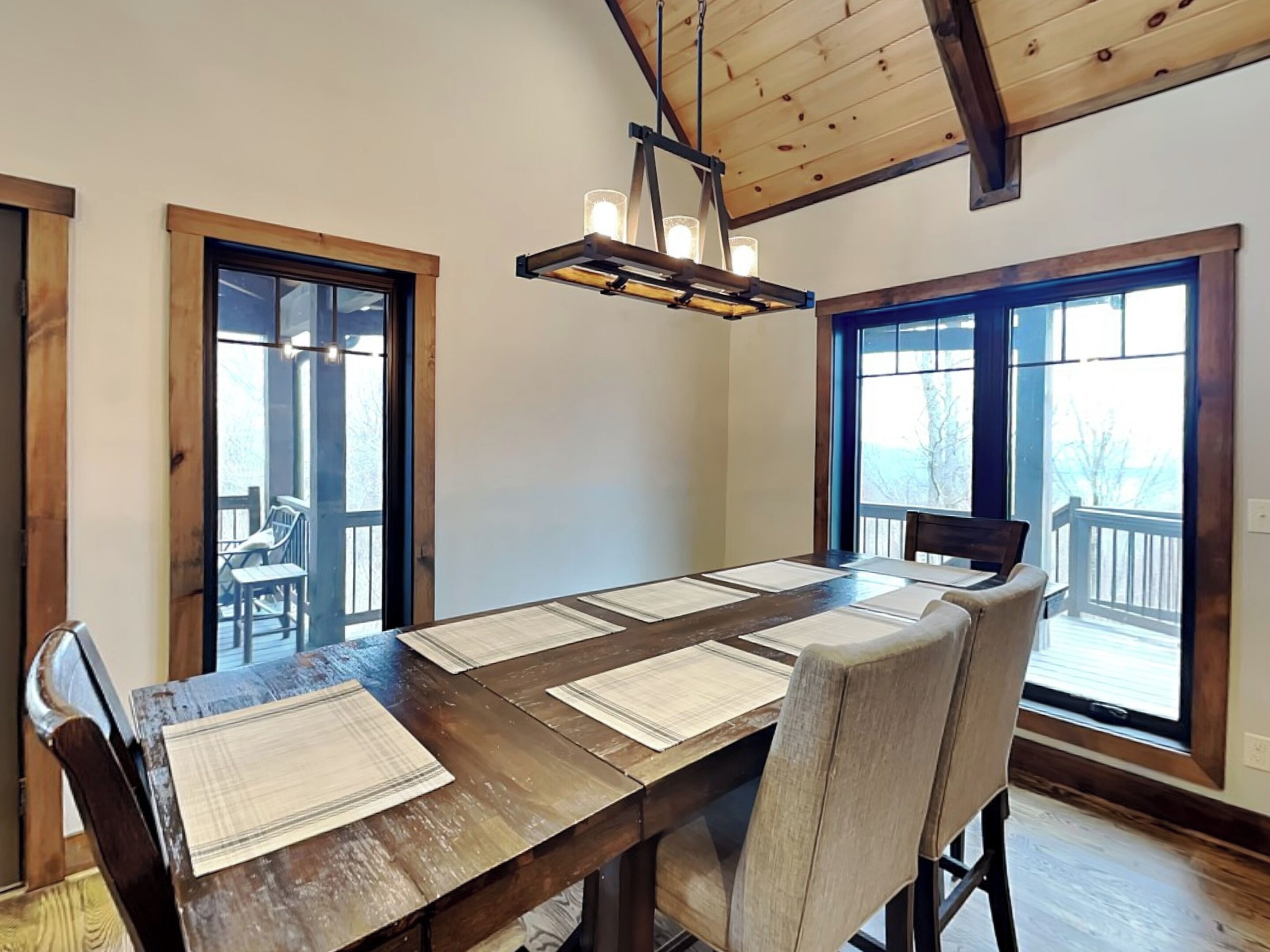 A dining area with a wooden table, chairs, and a hanging light fixture.
