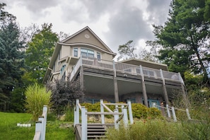 A two-story house with a balcony, a stone foundation, and a front porch with steps.