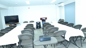 A conference room with a long table, chairs, a projector, and a television. - Lagun Hotel (El Nido)