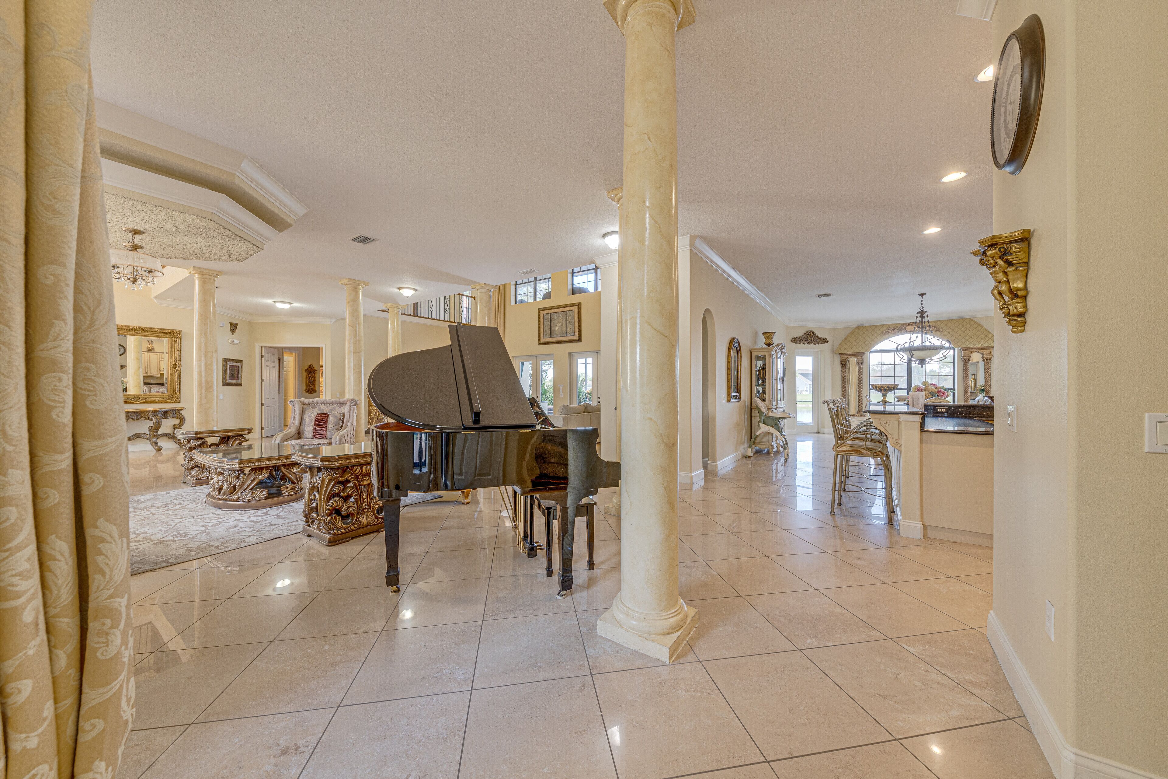 A spacious interior with a grand piano, elegant columns, and a chandelier.