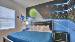 A bedroom with a bed, a nightstand, a dresser, and a wall mural.