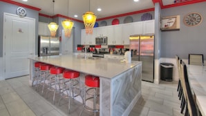 A modern kitchen with a large island, stainless steel appliances, and red bar stools.