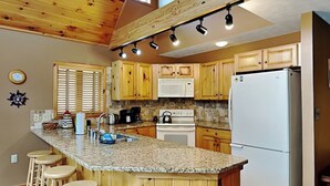 A kitchen with wooden cabinets, a granite countertop, a refrigerator, and a coffee maker.