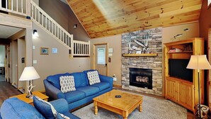 A living room with a blue sofa, wooden coffee table, fireplace, and a staircase.