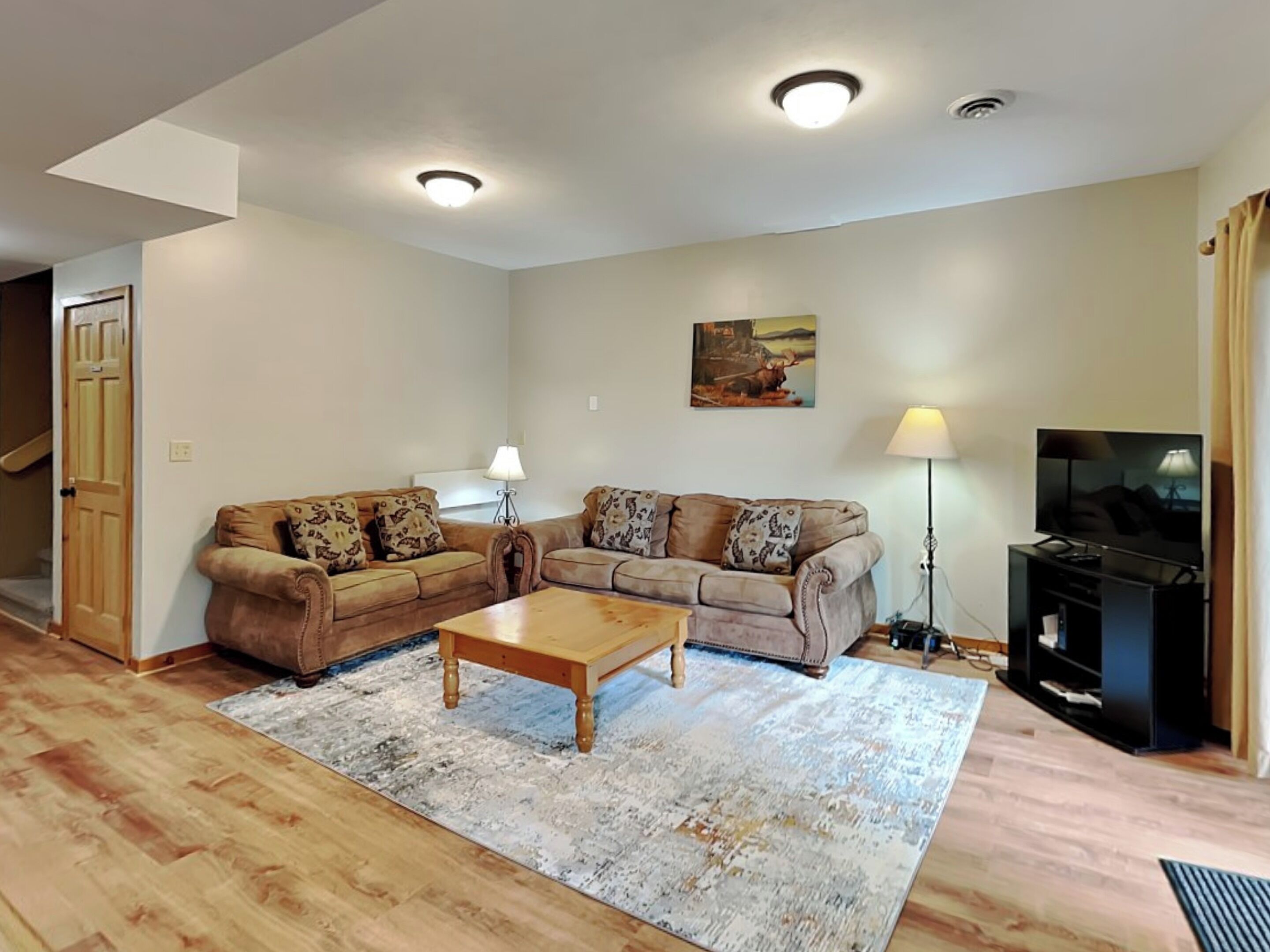A living room with a sofa set, a coffee table, a TV, and a painting on the wall.