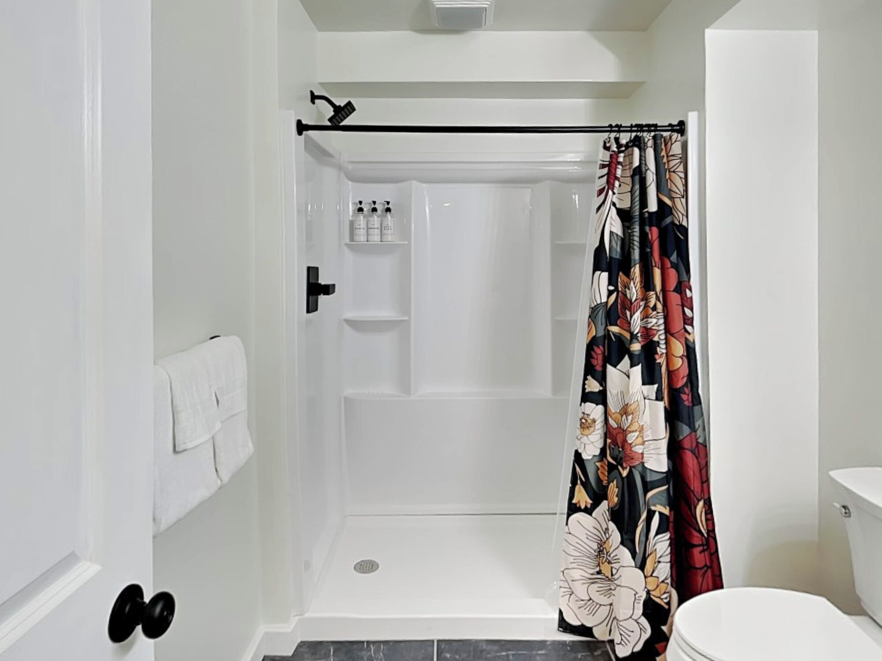 A bathroom with a shower, toilet, and a towel rack.