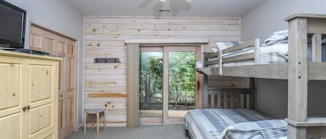 A bedroom with a bunk bed, a desk, a chair, a wardrobe, and a ceiling fan.