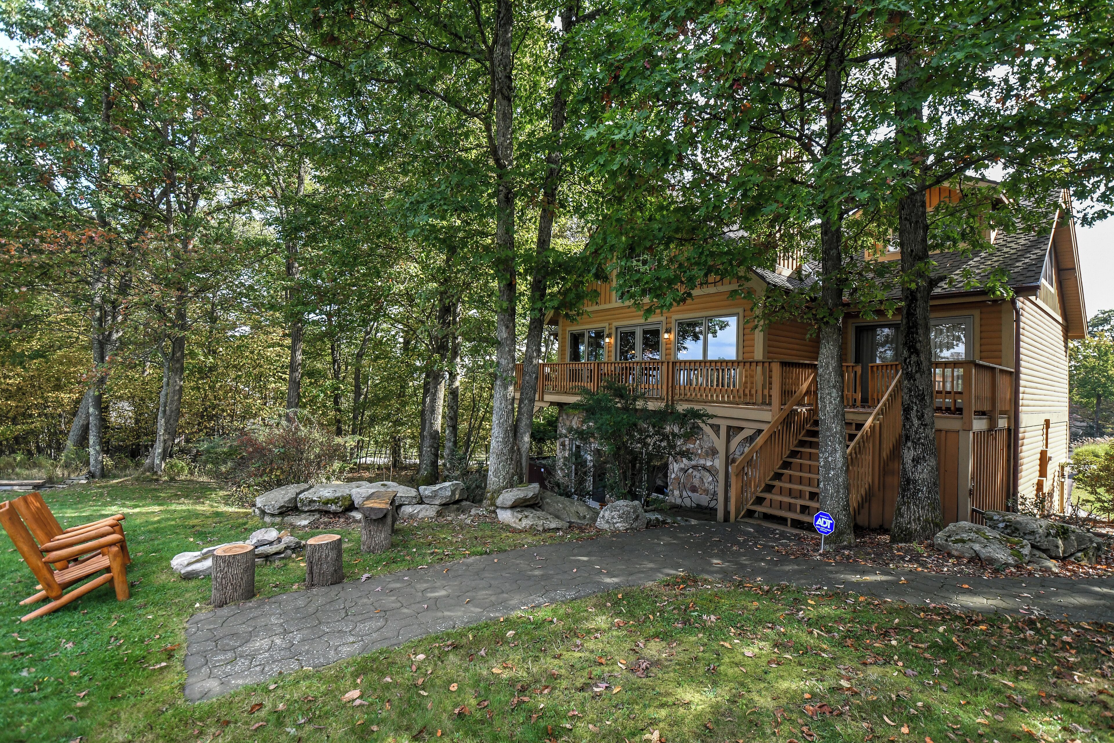 Une cabane en bois entourée d’arbres, avec un sentier de pierres menant à l’entrée.