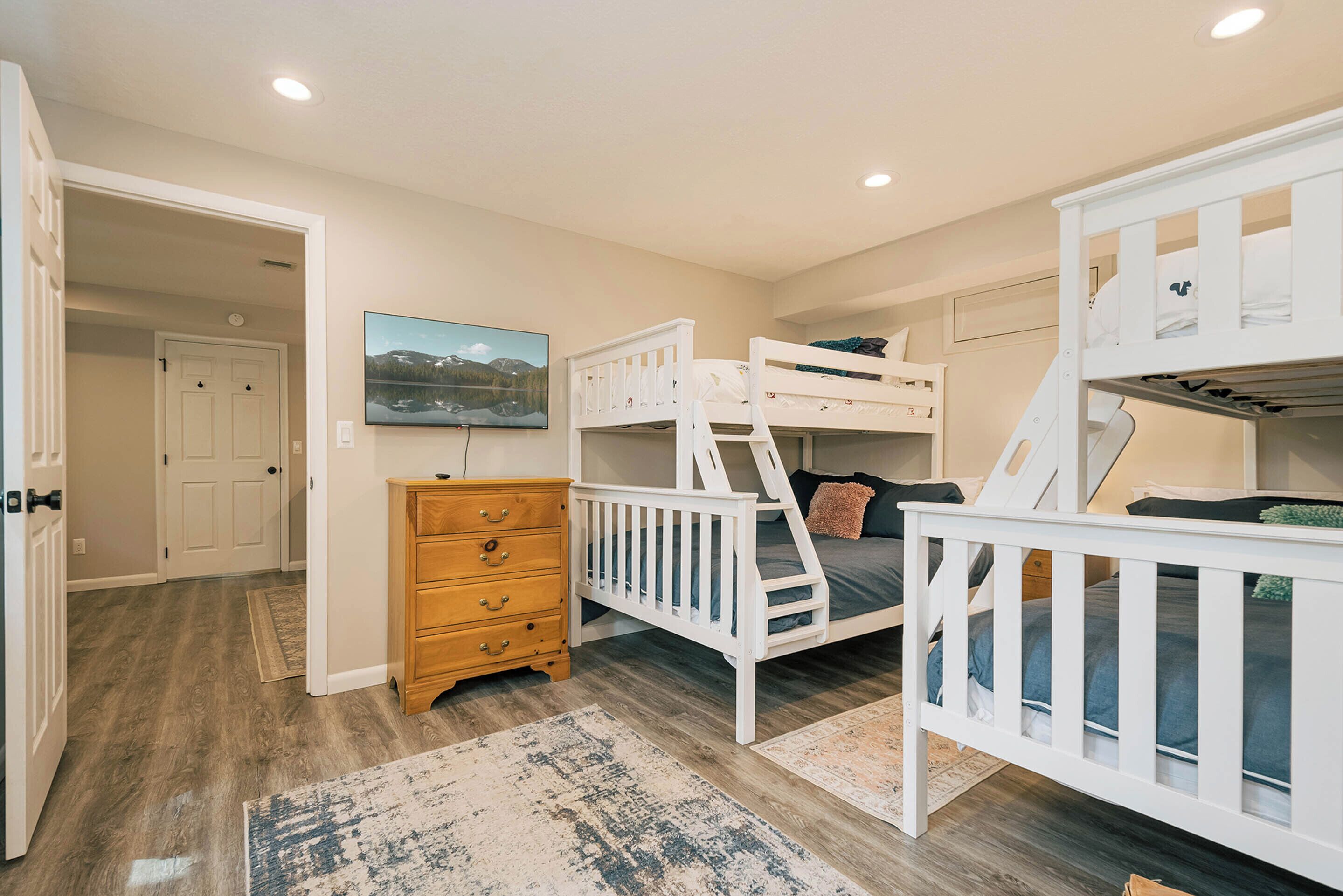 A room with bunk beds, a wooden dresser, and a painting on the wall.