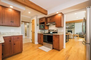 A modern kitchen with wooden cabinets, stainless steel appliances, and a wooden floor. - Alpine Cove by Taylor Made Deep Creek (Swanton)