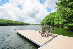 A wooden dock extending into a calm lake, surrounded by lush greenery. - Alpine Cove by Taylor Made Deep Creek (Swanton)
