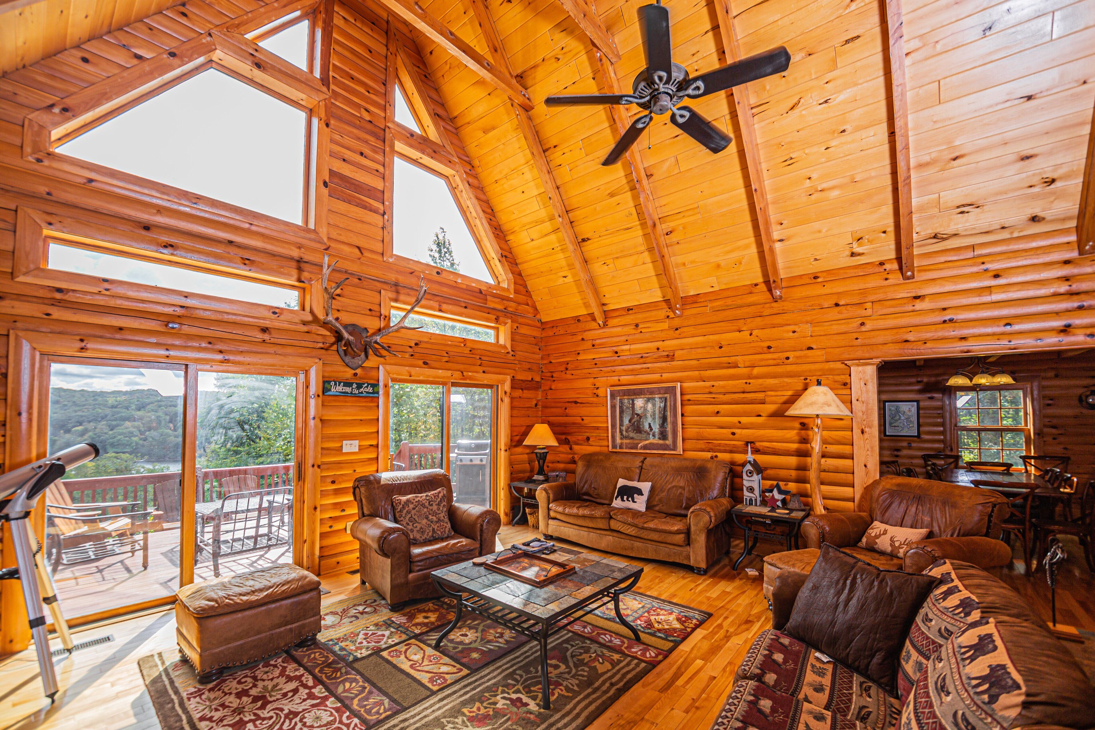 L’intérieur d’une cabane en rondins présente un grand espace de vie ouvert, un plafond en bois et un balcon offrant une vue panoramique.