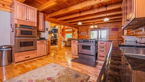 L’intérieur d’une cabane en bois comprend une cuisine équipée de deux fours, d’un réfrigérateur et de meubles de rangement en bois.