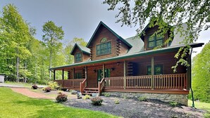 Une cabane en rondins dotée d’un porche, de fondations en pierre et d’une pelouse bien entretenue.