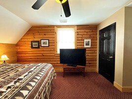 Un dormitorio con cama, televisor sobre un mueble, ventana y puerta.