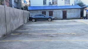 A parking area with a car parked in front of a building with a blue roof. - Senlan Hotel (Zhongxiang Bus Station Branch) (Zhongxiang)