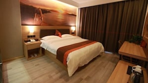 A hotel room with a large bed, a nightstand with a lamp, a wooden table with a coffee pot, and a view of the ocean through the window. - Senlan Hotel (Zhongxiang Bus Station Branch) (Zhongxiang)