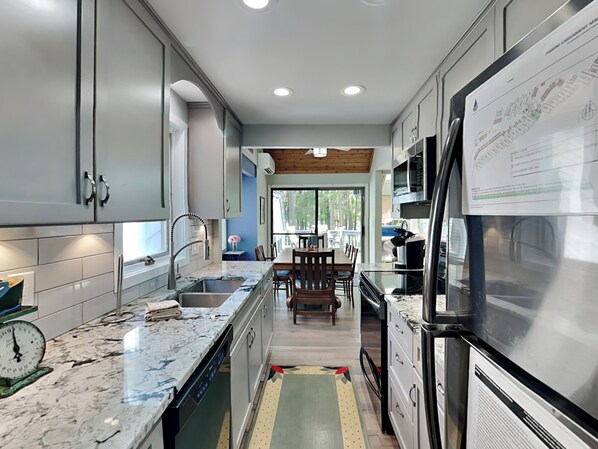 A modern kitchen with grey cabinets, a marble countertop, and stainless steel appliances. - Arrowhead Village 15 by Taylor Made Deep Creek (Oakland)
