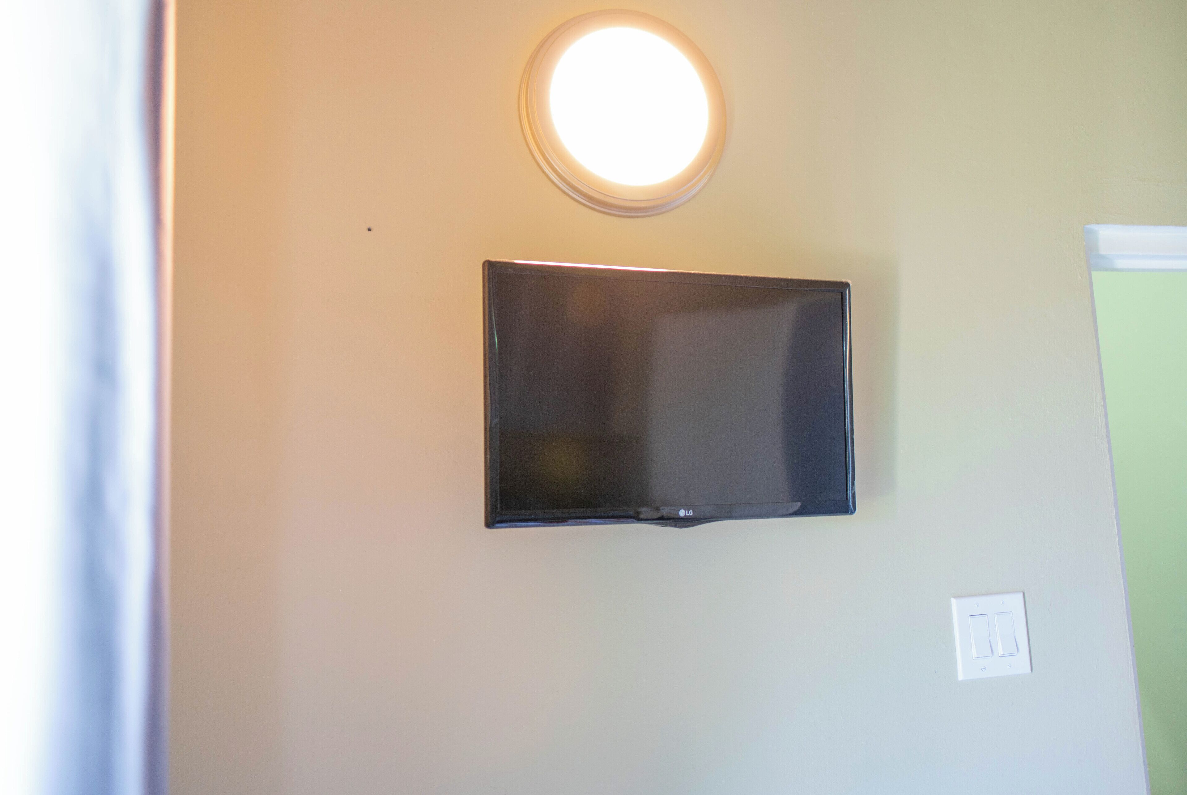 Una televisione a schermo piatto montata a parete, con una luce a soffitto sopra.