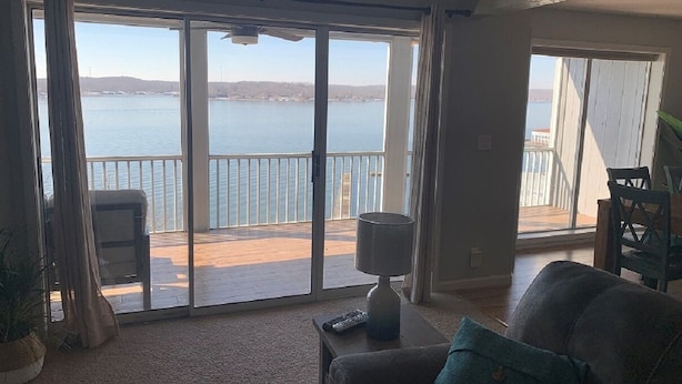 Sala de estar com vista para um corpo d'água através de grandes portas de vidro deslizantes.