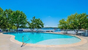 Piscina com céu azul límpido e árvores ao fundo.