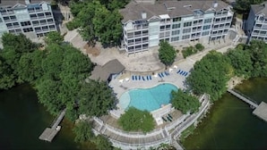 Vista aérea de um prédio residencial com piscina, rodeado por árvores.
