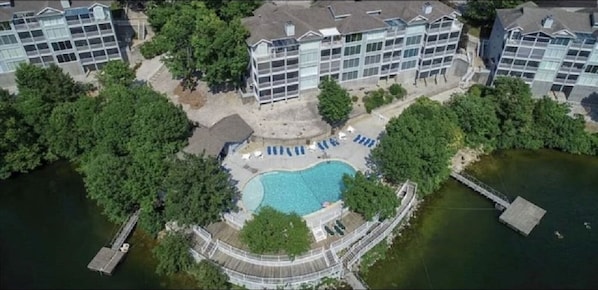 An aerial view of a residential building with a swimming pool surrounded by trees.