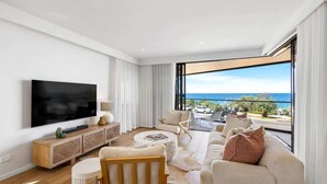 Una sala de estar moderna con un televisor de pantalla plana grande, un mueble bajo de madera, un sofá y una mesa de centro.