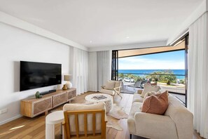 Un salon moderne avec un grand téléviseur à écran plat, une console en bois, un canapé et une table basse.