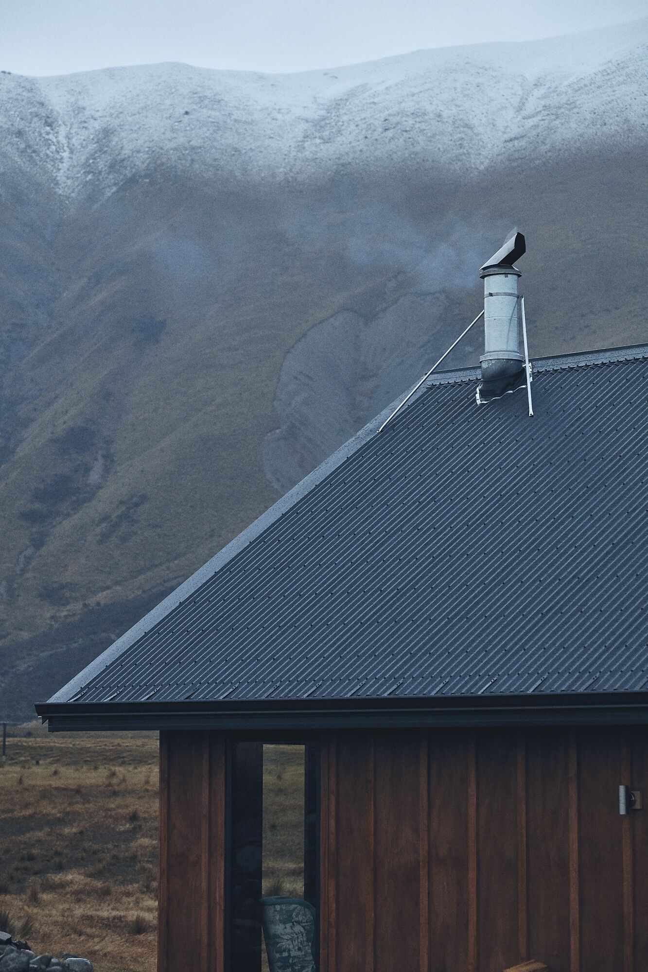 Un bâtiment avec un toit sombre et une cheminée.