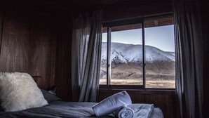 Una habitación con cama, ventana y vista a un paisaje nevado.