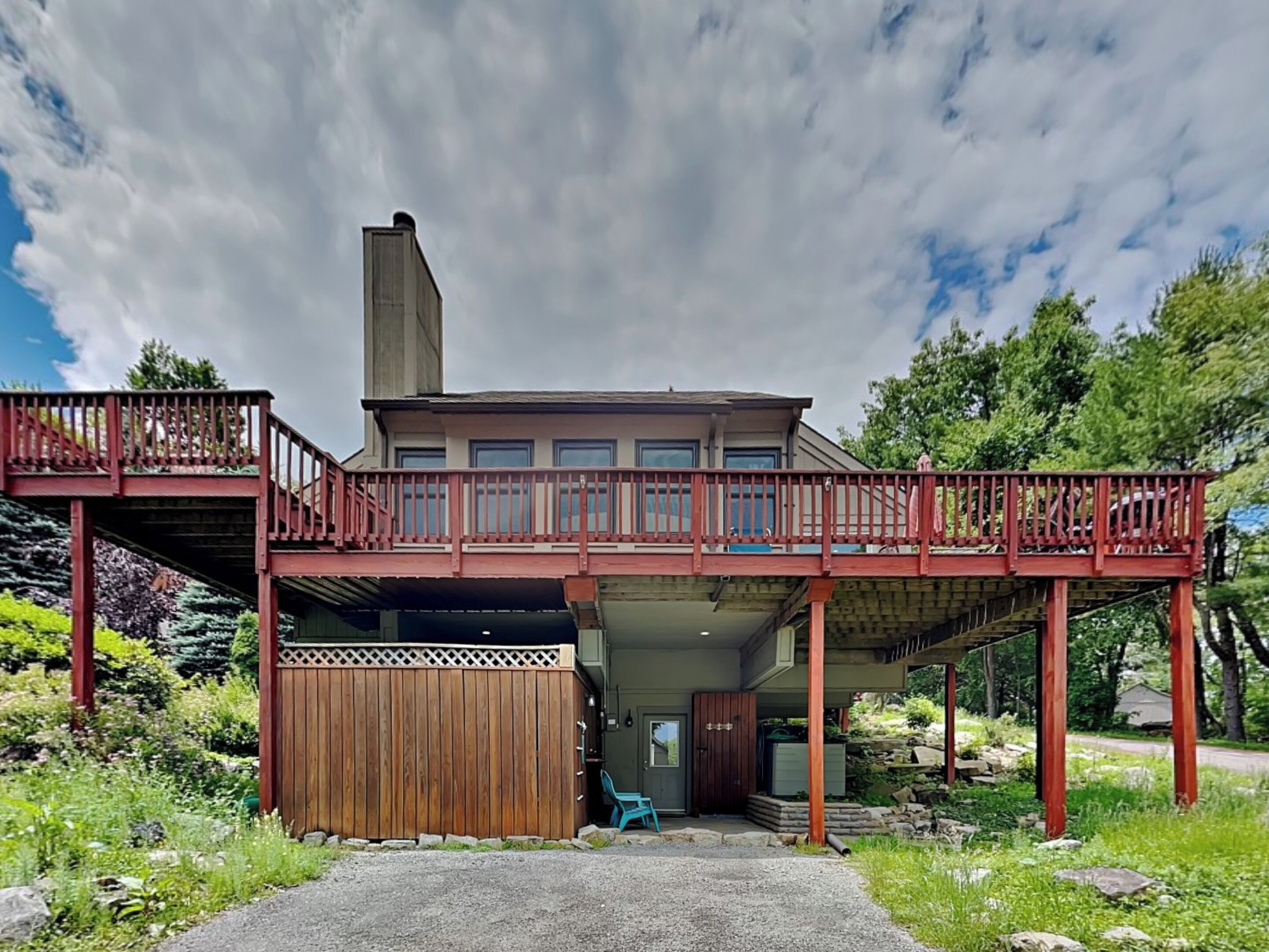 Une maison à deux étages avec un porche couvert et une clôture en bois.